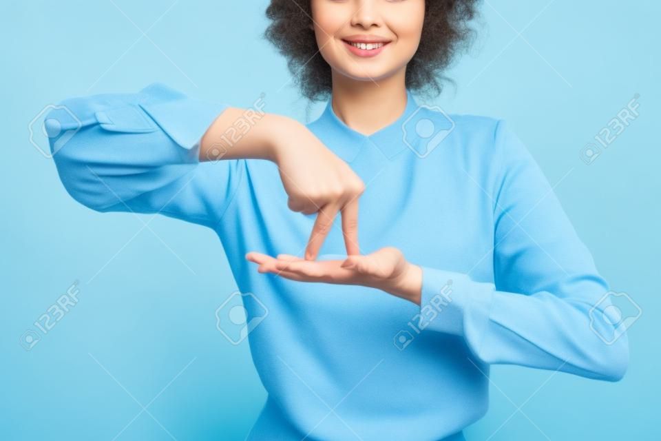 青の背景に手話に立つジェスチャーの意味を示すポジティブな教師の部分的なビュー