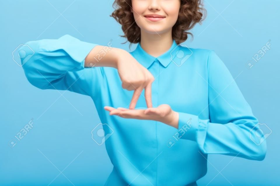 partial view of positive teacher showing gesture meaning stand on sign language isolated on blue