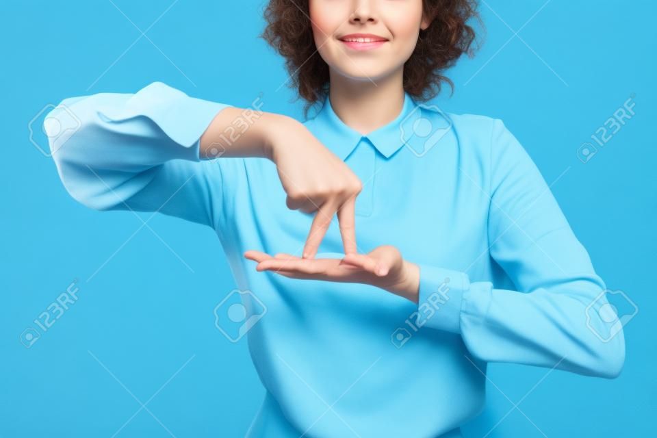 青の背景に手話に立つジェスチャーの意味を示すポジティブな教師の部分的なビュー