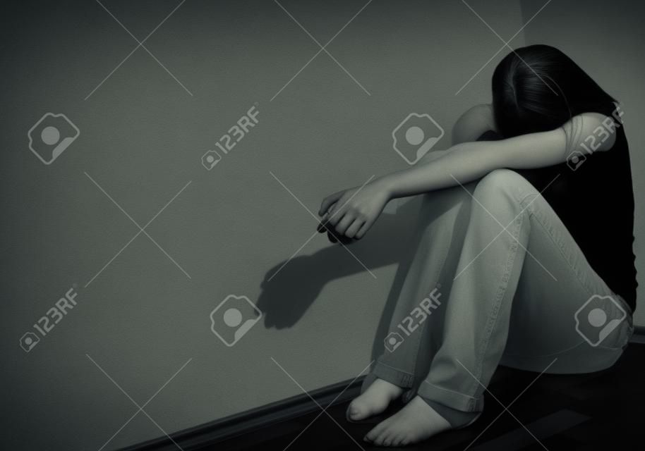 Young woman suffering from a severe depression
 (very harsh lighting is used on this shot to underline/convey the gloomy mood of the scene)