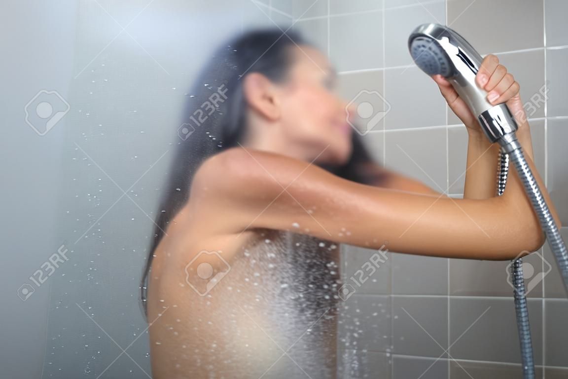 Woman taking a long hot shower washing her hair in a modern design bathroom