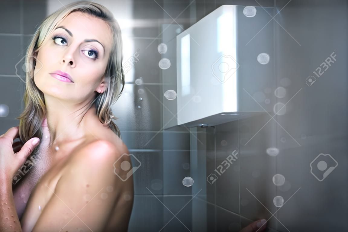 Mujer tomando una larga ducha caliente lavándose el pelo en un baño de diseño moderno