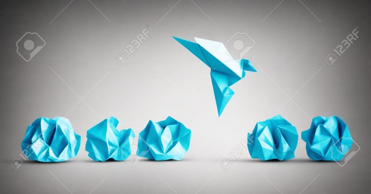 Concept of new idea and creative thinking as a symbol of innovation and inspiration metaphor as a group of crumpled papers with one different paper transforming into an origami bird in flight.