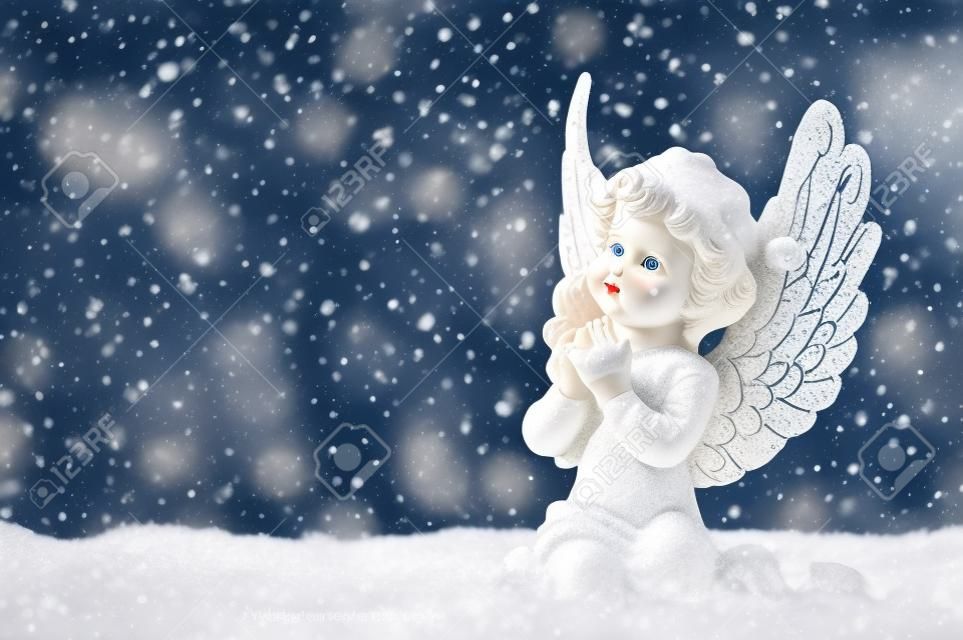 peu de blanc ange gardien dans la neige sur fond de bois. cru décoration de Noël de style avec effet chute de flocons de neige