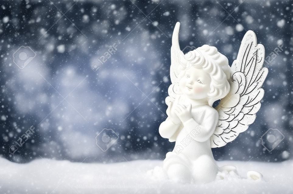 나무 배경에 눈이 작은 흰색 수호 천사. 떨어지는 눈송이 효과 빈티지 스타일 크리스마스 장식