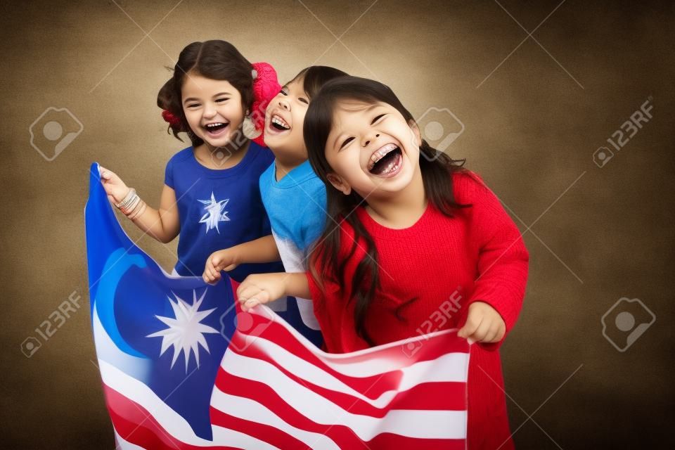 Trzy dziewczyny trzymające flagę, śmiejące się