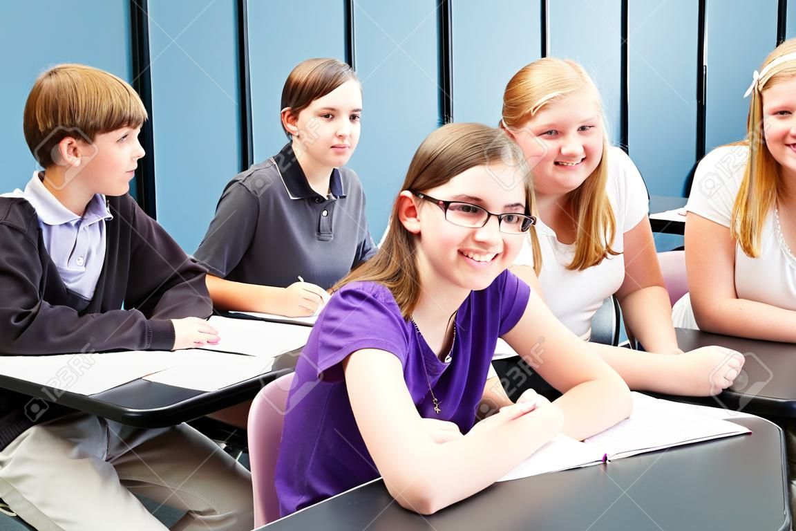 Six enfants d'âge scolaire des adolescents assis à des tables en classe.