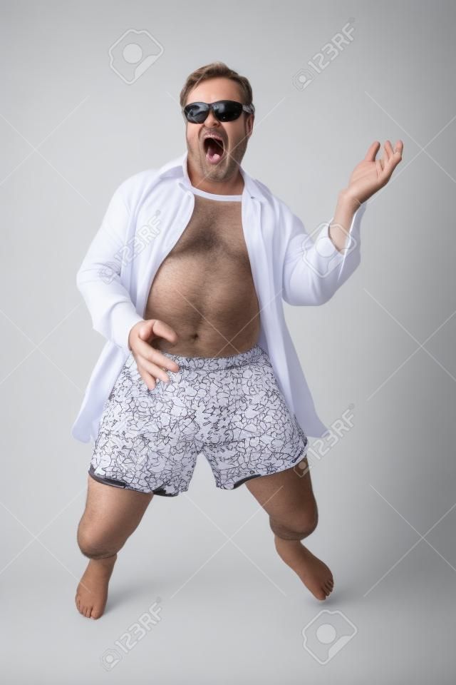 Смешные фото среднего возрасте человек, играя на гитаре воздуха в нижнем белье. Полное тело, изолированных на белом фоне.