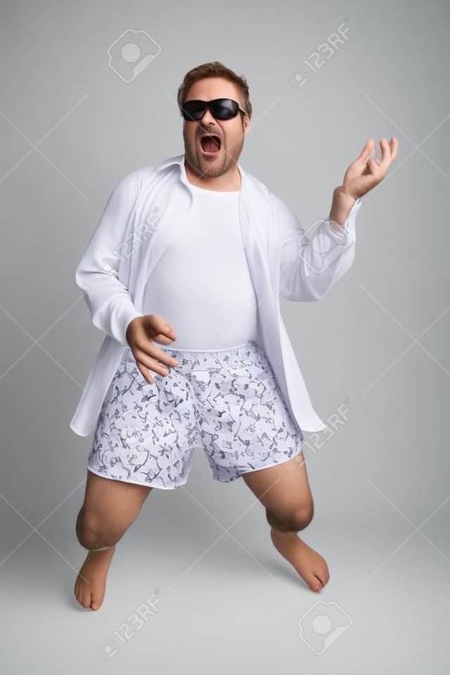 Photo drôle d'un homme d'âge mûr jouer de la guitare de l'air dans ses sous-vêtements. Complet du corps isolé sur blanc.