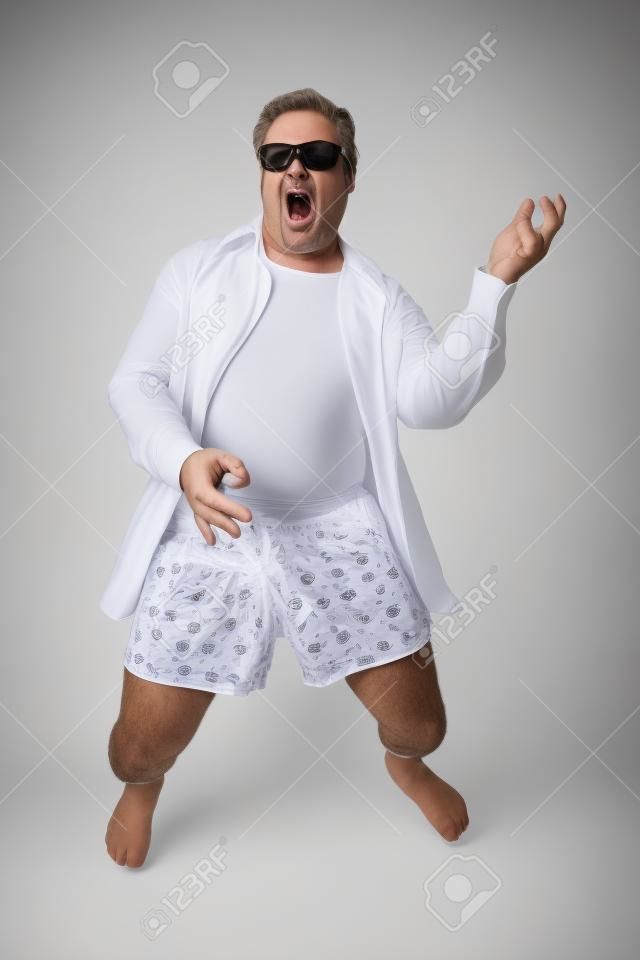 Photo drôle d'un homme d'âge mûr jouer de la guitare de l'air dans ses sous-vêtements. Complet du corps isolé sur blanc.