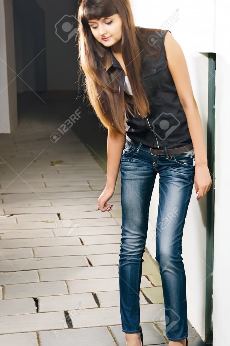 Portrait of a beautiful slender young model posing in jeans.