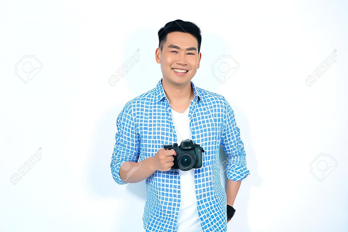 Happy asian man holding camera and smiling at camera against white background