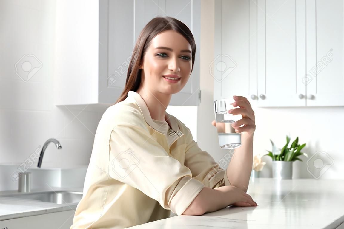 Vrouw met glas kraanwater in de keuken