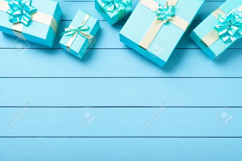 Many colorful gift boxes on light blue wooden table, flat lay. Space for text
