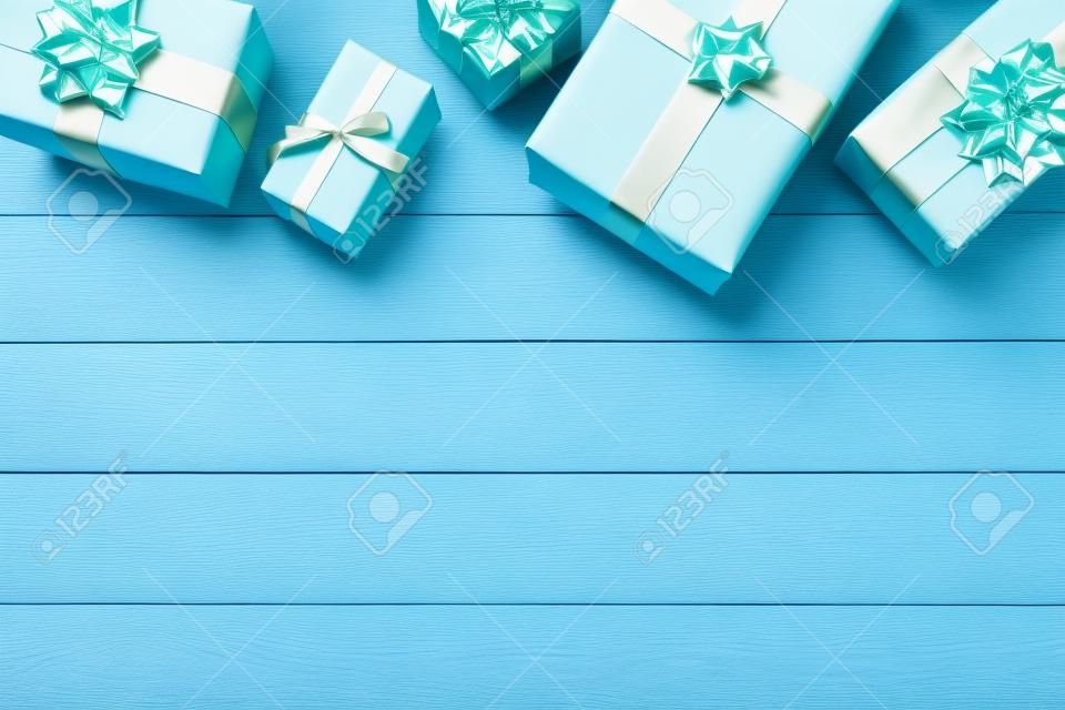 Many colorful gift boxes on light blue wooden table, flat lay. Space for text