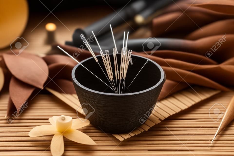Composition with acupuncture needles on black wooden table