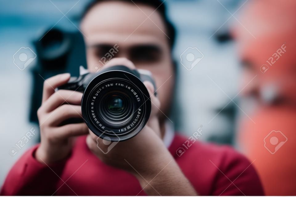 Fotograf fotografiert mit professioneller Kamera im Freien, Fokus auf Objektiv
