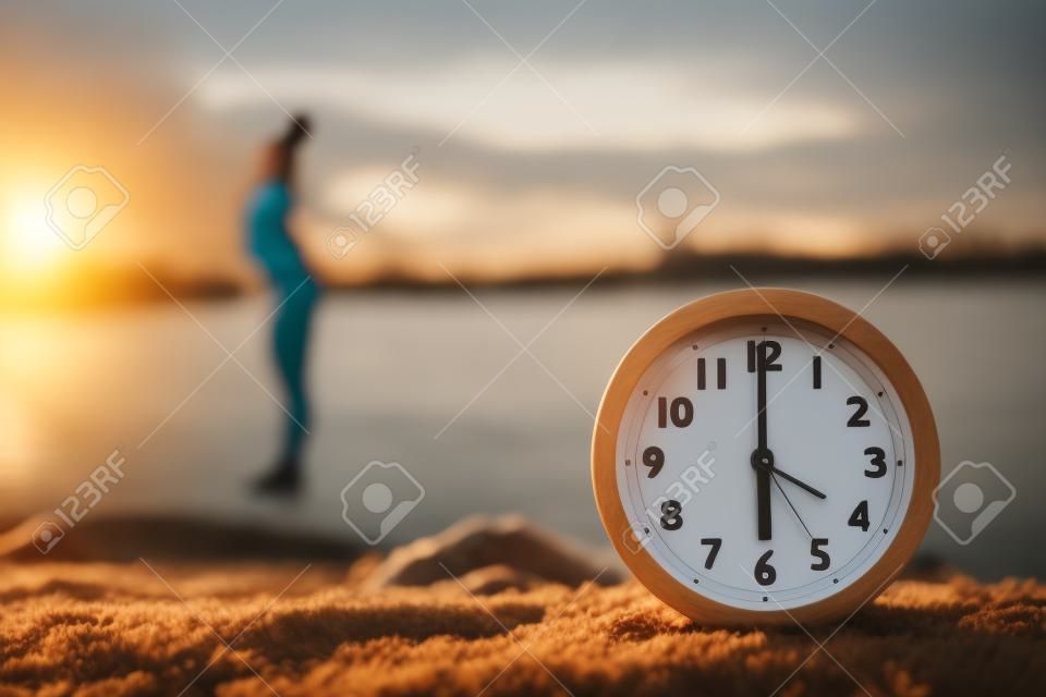 Donna che fa esercizi mattutini vicino al fiume all'aperto, concentrarsi sulla sveglia