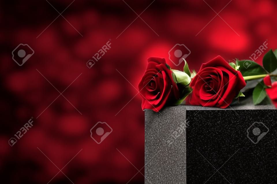 Rote Rosen auf schwarzem Granitgrabstein im Freien, Platz für Text. Begräbniszeremonie