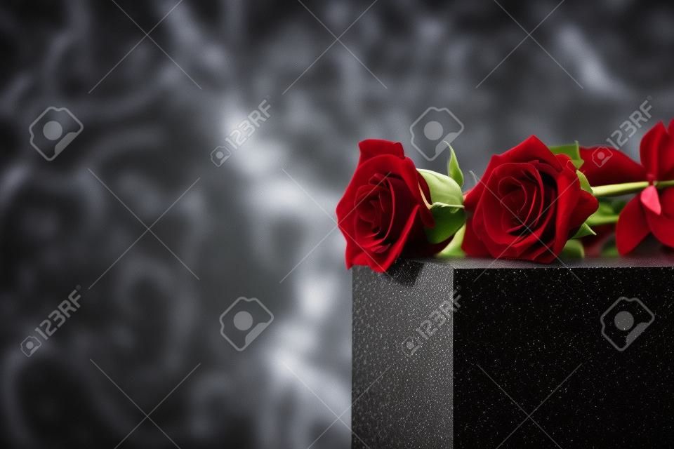 Rote Rosen auf schwarzem Granitgrabstein im Freien, Platz für Text. Begräbniszeremonie