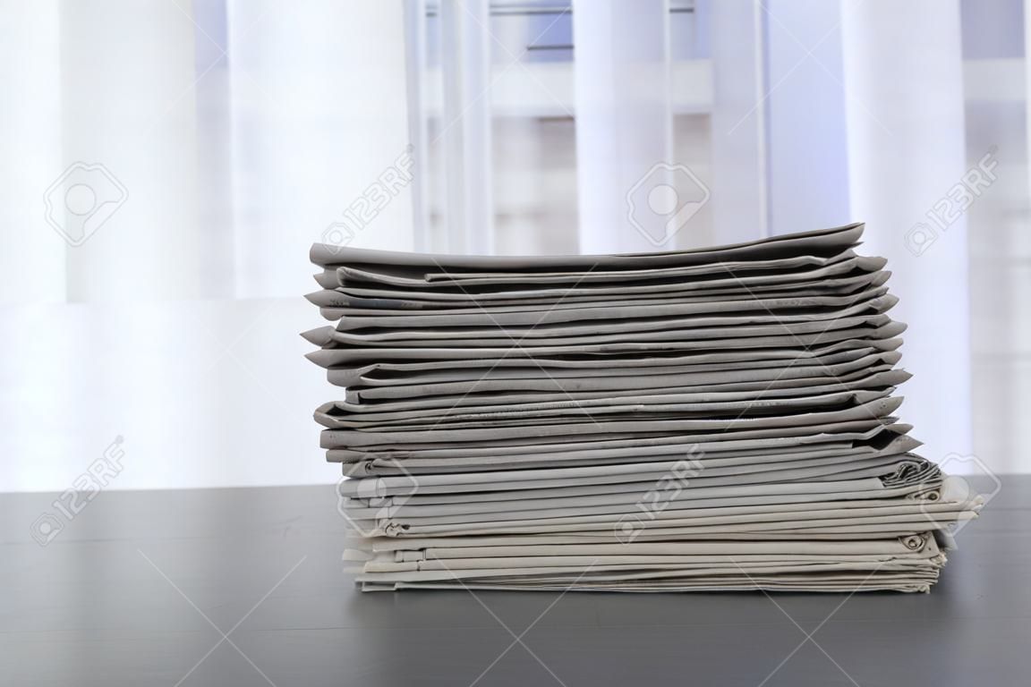 Stack van kranten op grijze tafel, ruimte voor tekst.
