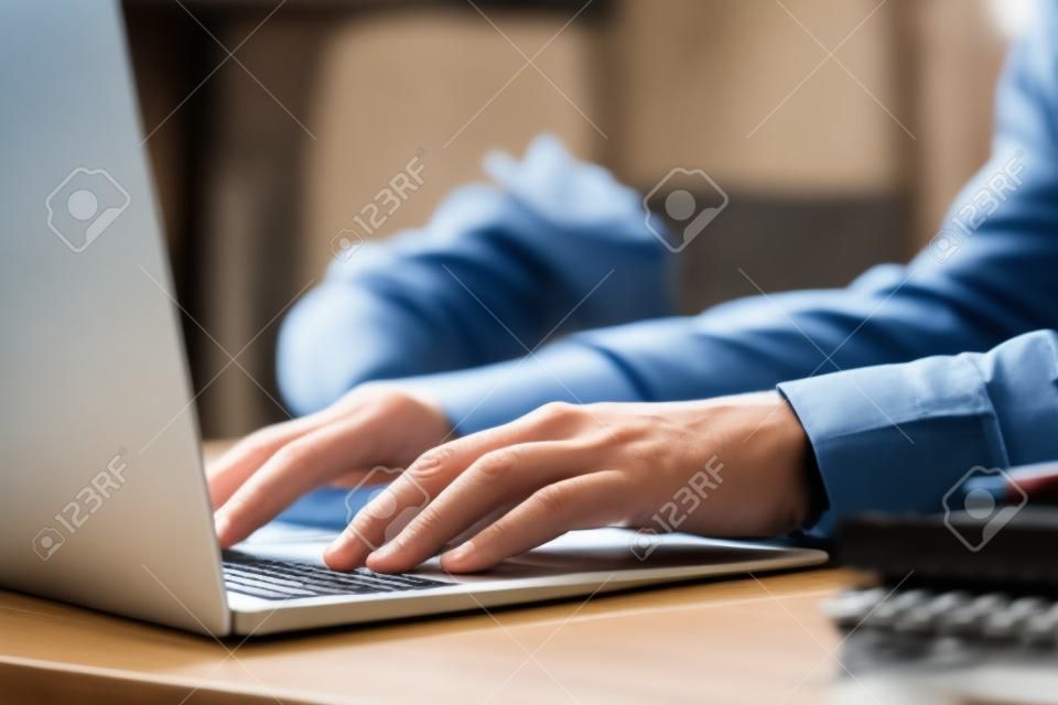 Journaliste travaillant avec un ordinateur portable à table, gros plan