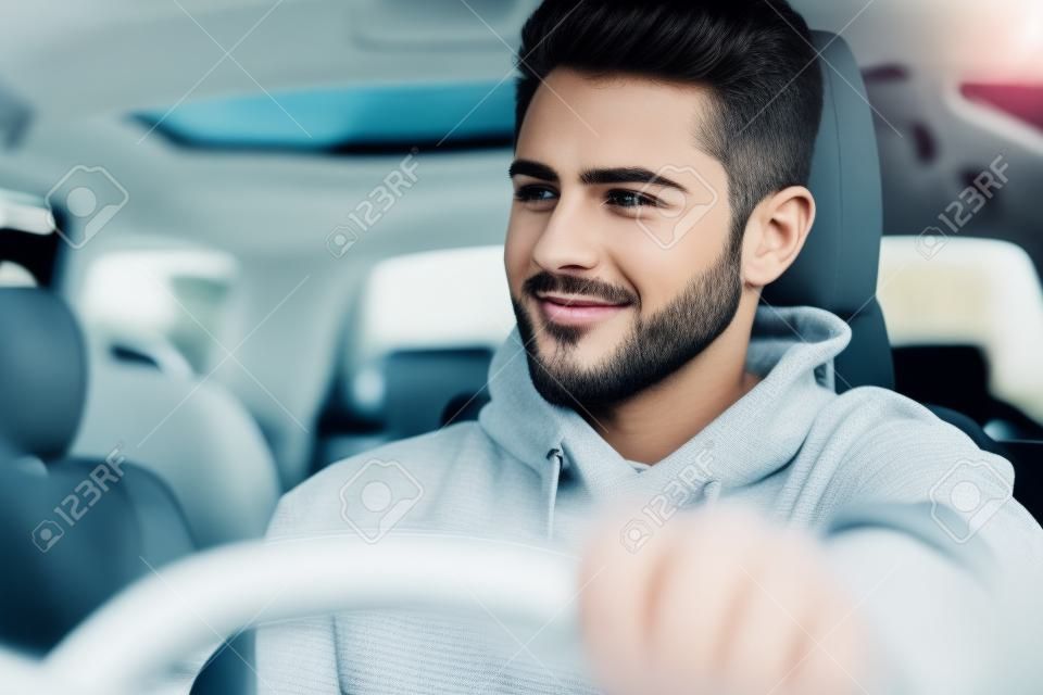 Beau jeune homme au volant de sa voiture moderne