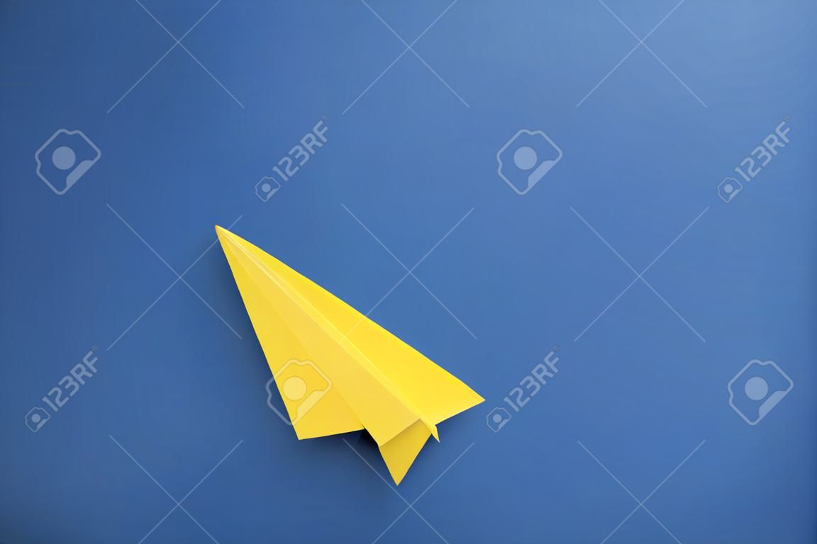 Aereo di carta giallo su sfondo blu, vista dall'alto. spazio per il testo