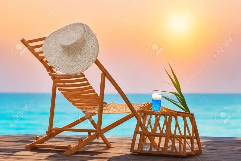 Liegestuhl aus Holz und Korbtisch mit Getränk in der Nähe der Sommerferien am Meer