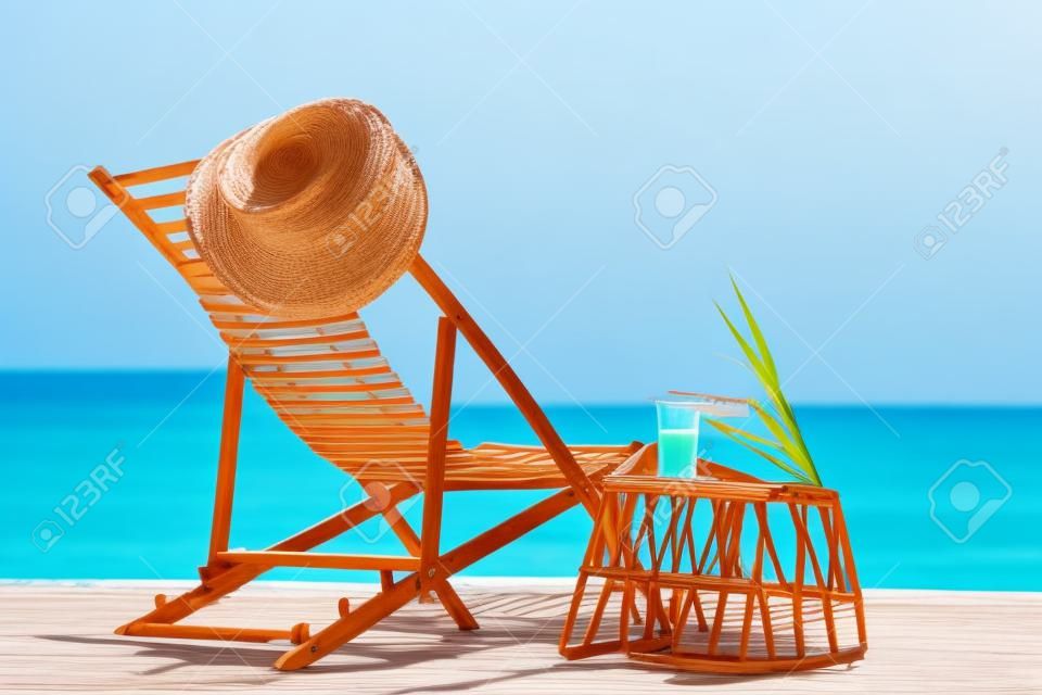 Liegestuhl aus Holz und Korbtisch mit Getränk in der Nähe der Sommerferien am Meer