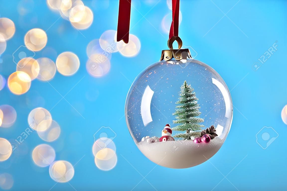 Decorative snow globe hanging on against blurred festive lights, closeup. Space for text