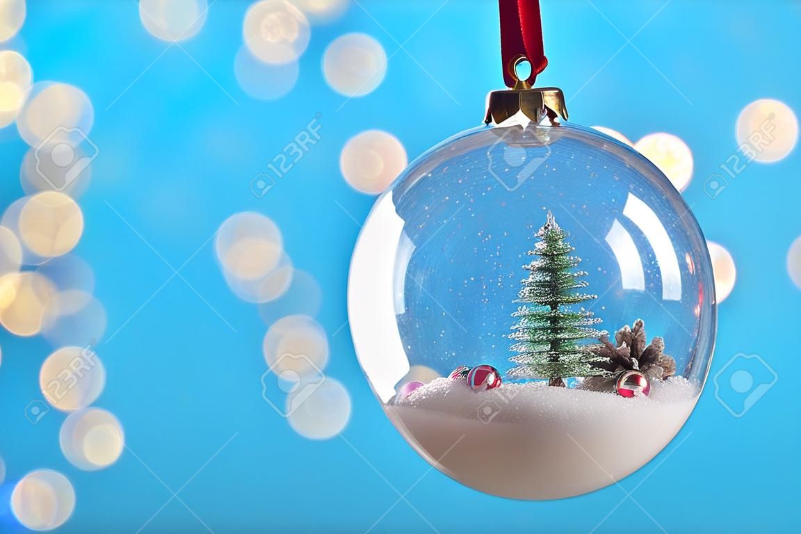 Decorative snow globe hanging on against blurred festive lights, closeup. Space for text