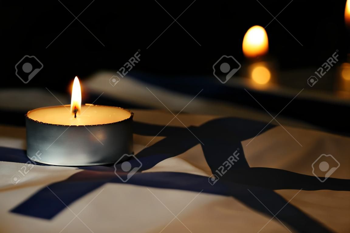 Burning candle on flag of Israel. Holocaust memory day