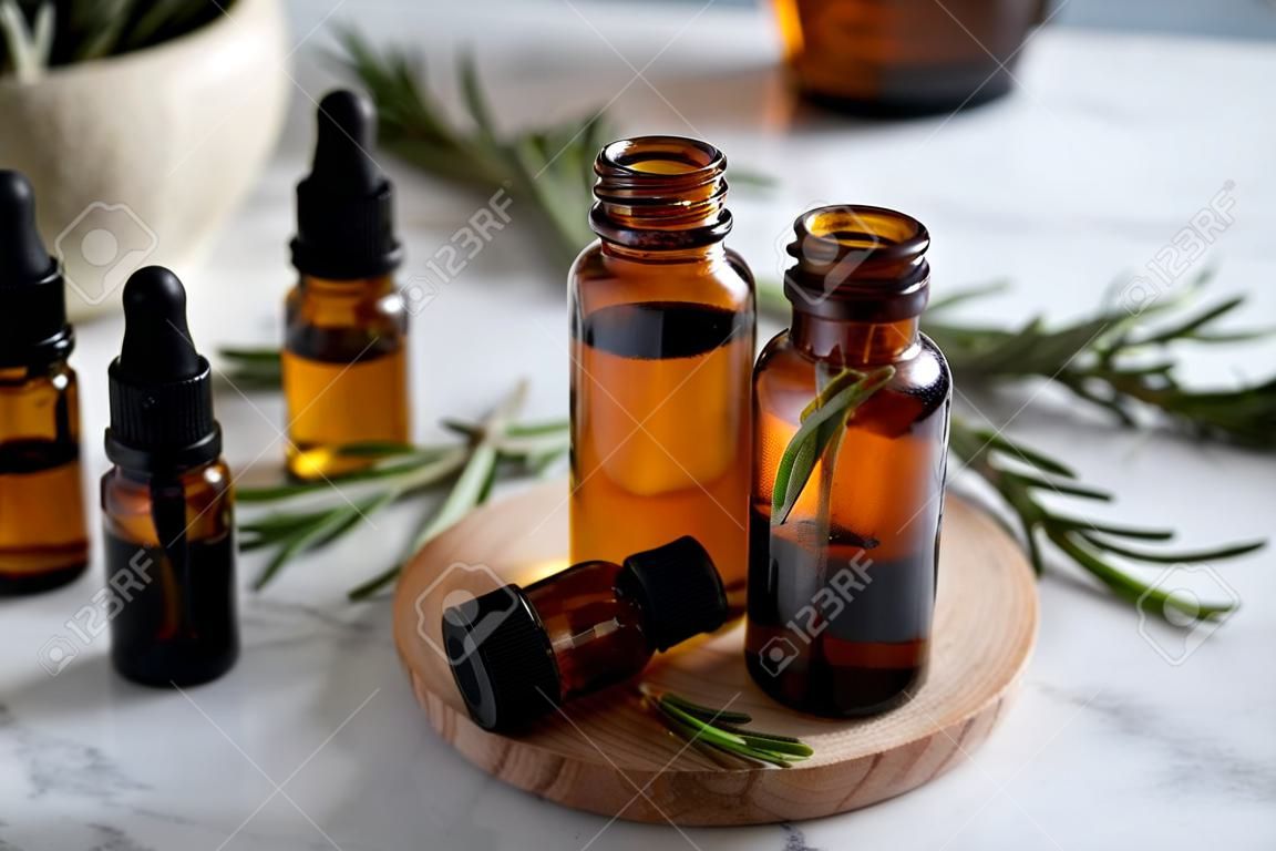 Bottles with rosemary essential oil on table