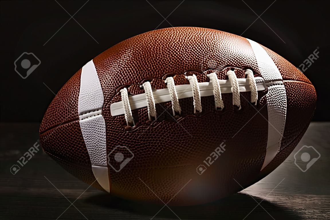 Neuer American-Football-Ball auf dem Tisch vor dunklem Hintergrund