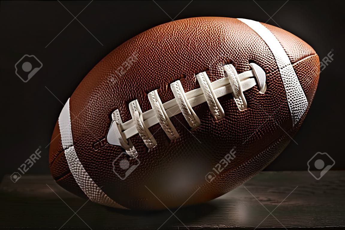 Neuer American-Football-Ball auf dem Tisch vor dunklem Hintergrund