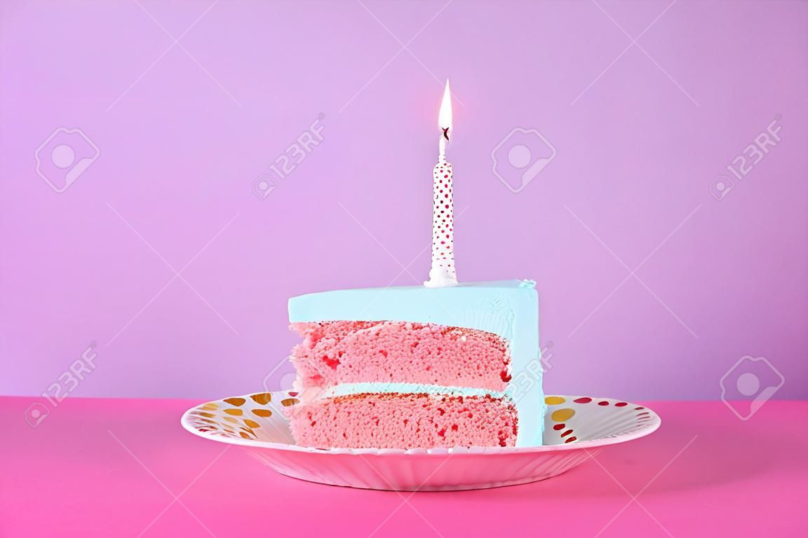 Slice of fresh delicious birthday cake with candle on table against color background