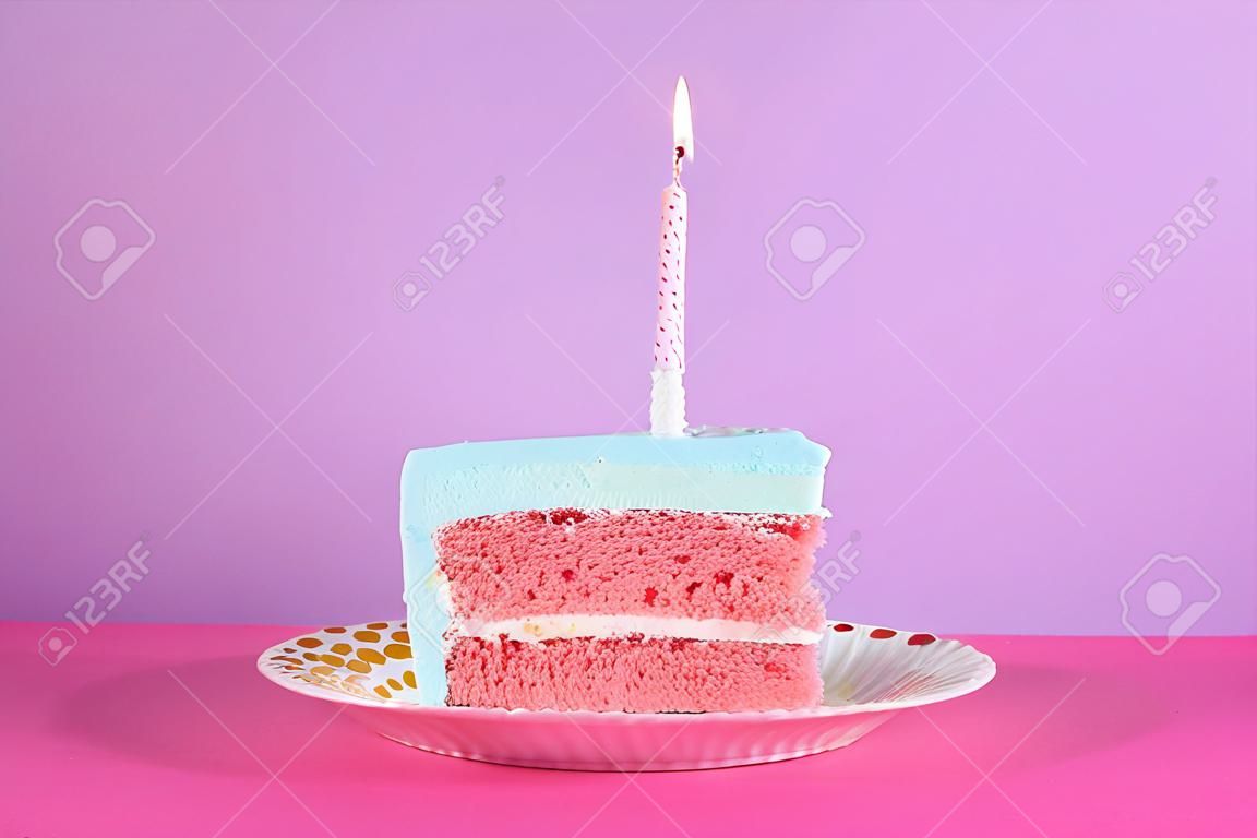 Plakje verse, heerlijke verjaardagstaart met kaars op tafel tegen een achtergrond met kleur