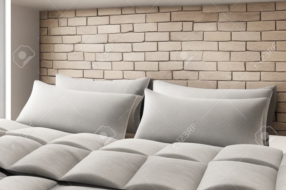 Large comfortable bed with pillows and blanket near white brick wall indoors. Stylish interior