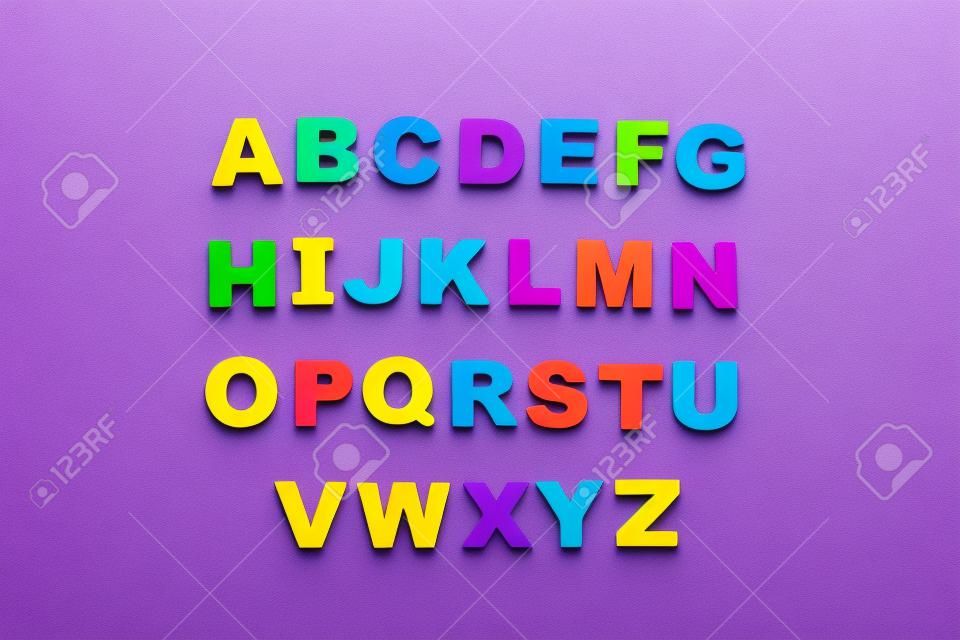 Letras magnéticas coloridas sobre fondo violeta orden alfabético plano