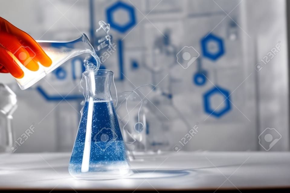 Científico que trabaja con cristalería de laboratorio y espacio para texto en la reacción química de primer plano de la mesa de madera