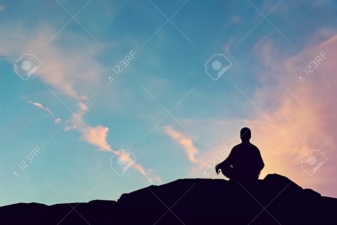 man meditating pastel on high mountain in sunset background.