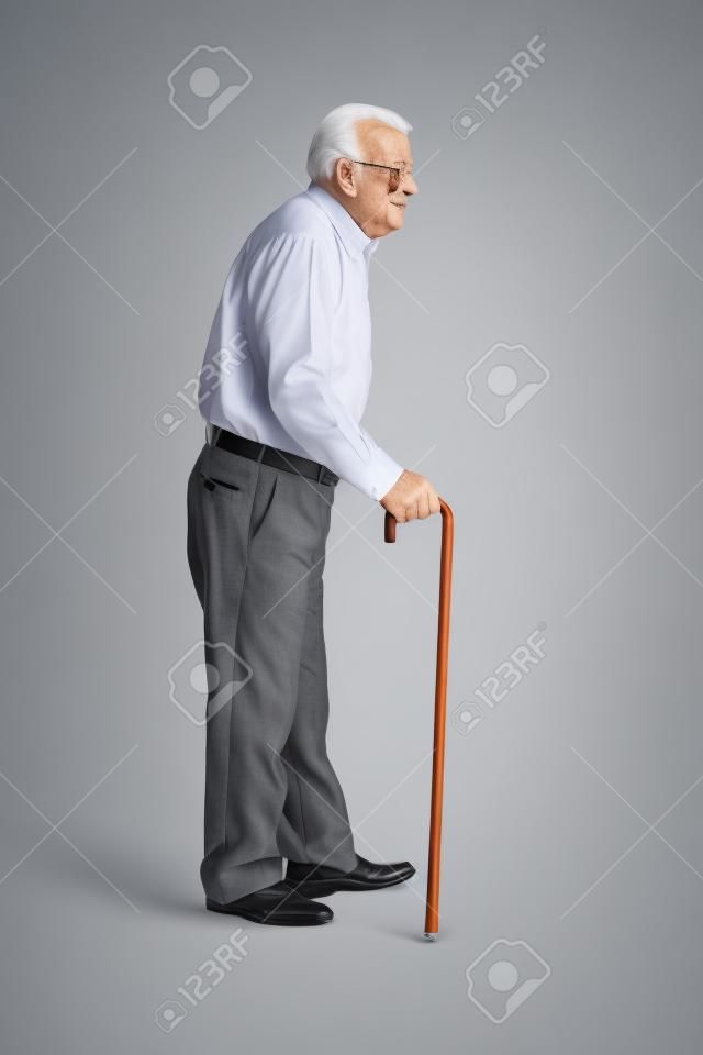 Retrato de cuerpo entero de un hombre mayor caminando con un bastón aislado en el fondo blanco