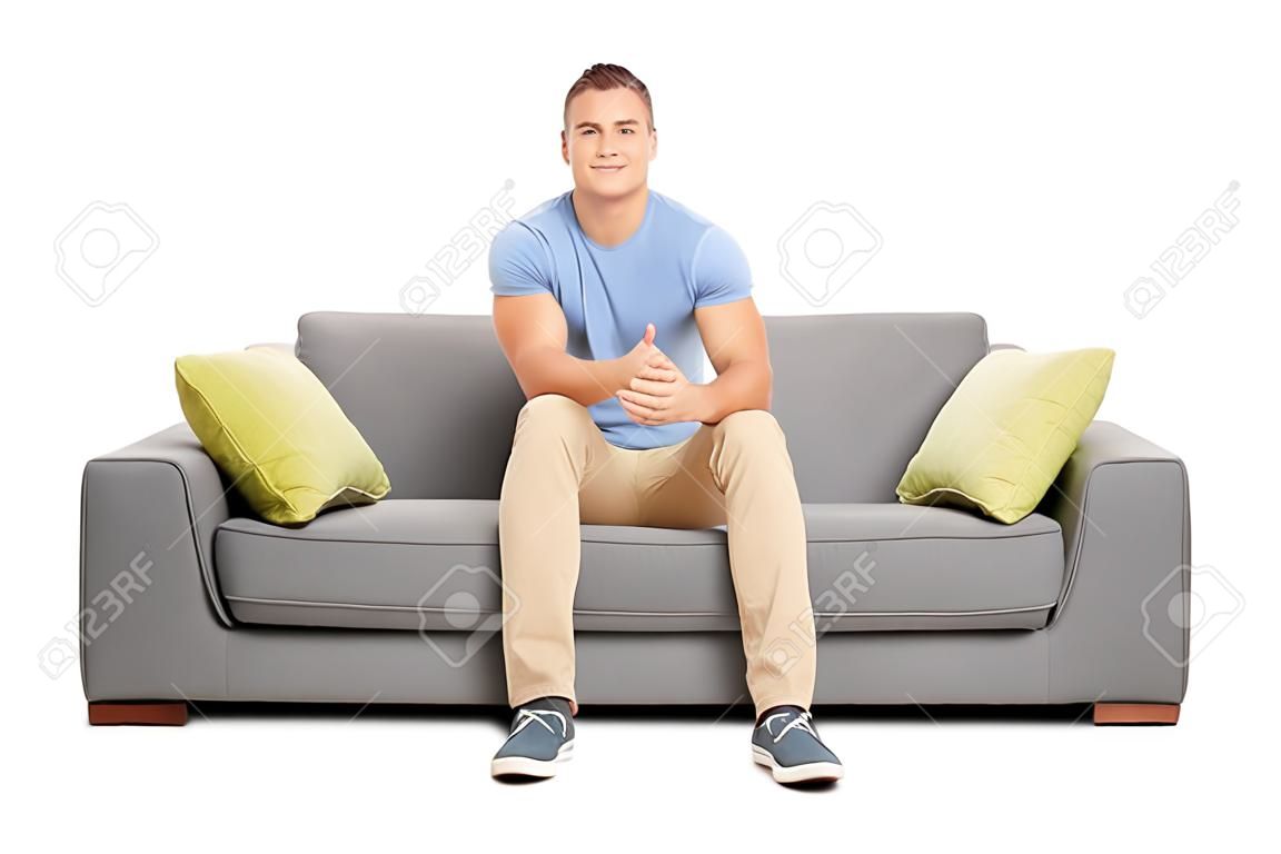 Apuesto joven sentado en un sofá moderno aislado en el fondo blanco