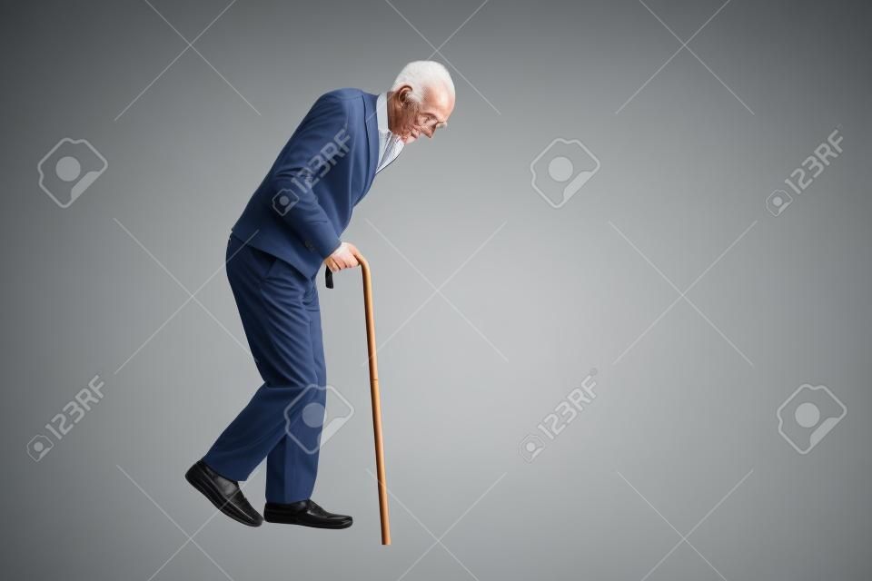Studio photo d'un vieil homme épuisé marche avec une canne isolé sur fond blanc