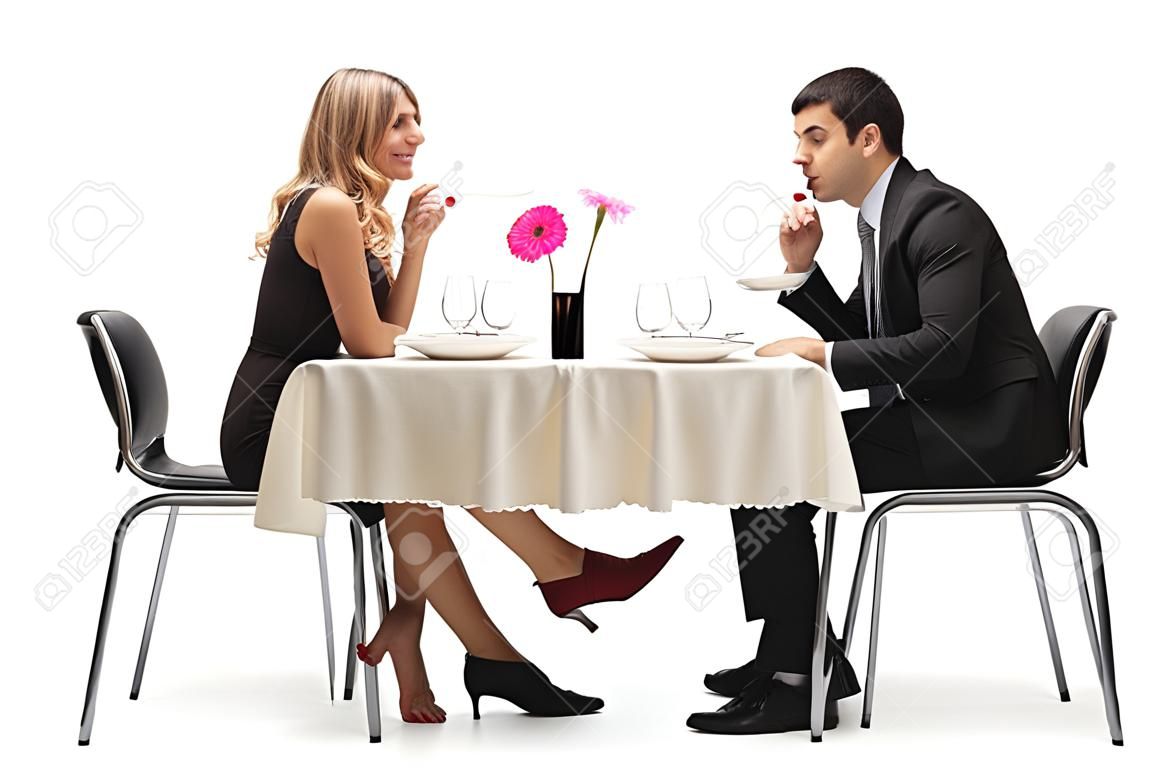 Mujer joven que toca un hombre debajo de la mesa con el pie aislado en fondo blanco