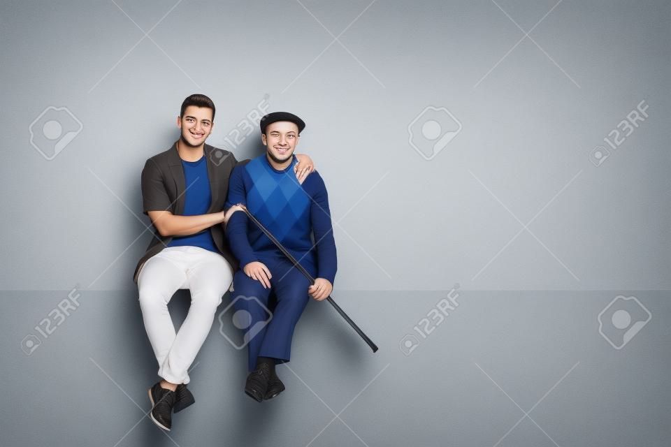Homem novo e um sênior que sentam-se em um painel junto isolado no fundo branco