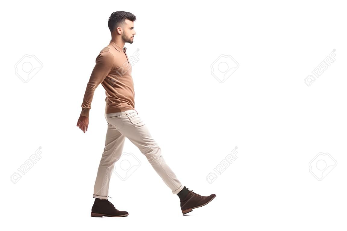 Profil de pleine longueur tourné d'un jeune homme marchant isolé sur fond blanc