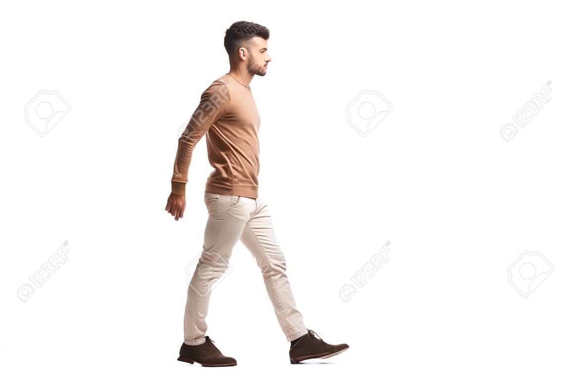 Profil de pleine longueur tourné d'un jeune homme marchant isolé sur fond blanc