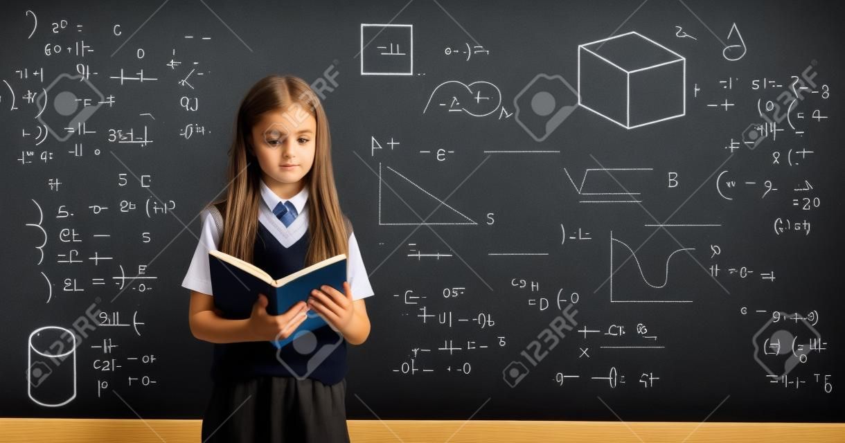 Uczeń czytający książkę i stojący przed tablicą z formułami geometrycznymi i matematycznymi